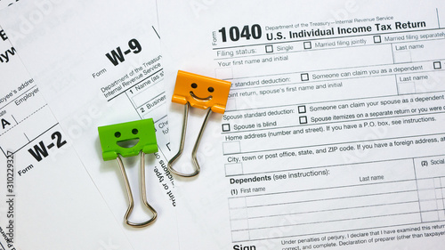 IRS 1040, W-9 and W-2 U.S. Tax Form with Green and Orange Color Binder Clips. Wage and tax statement concept photo