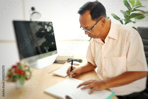 Asian old businessman working on tablet computer in office