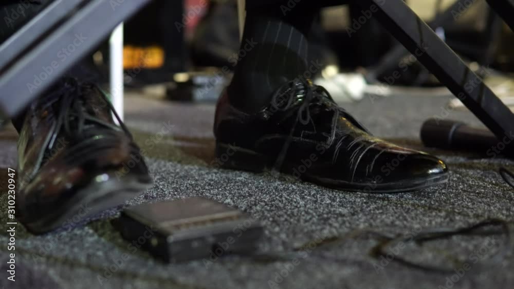 The foot of the musician stomps to the beat of the music. A man in shoes beats the beat to the music. Close-up.