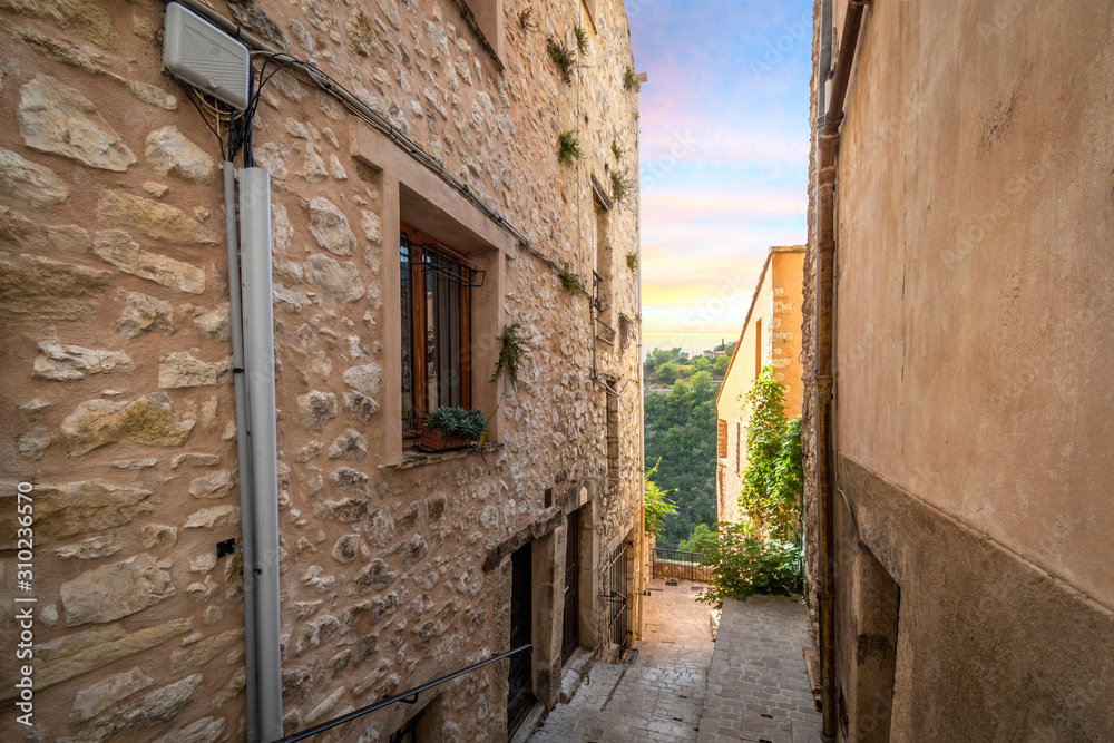Sunset and mountain view through an alley in the medieval stone village of Tourrettes Sur Loup in the south of France.