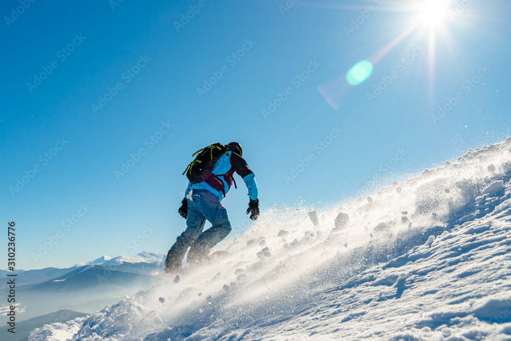 Snowboarder Riding Snowboard in Mountains at Sunny Day. Snowboarding and Winter Sports