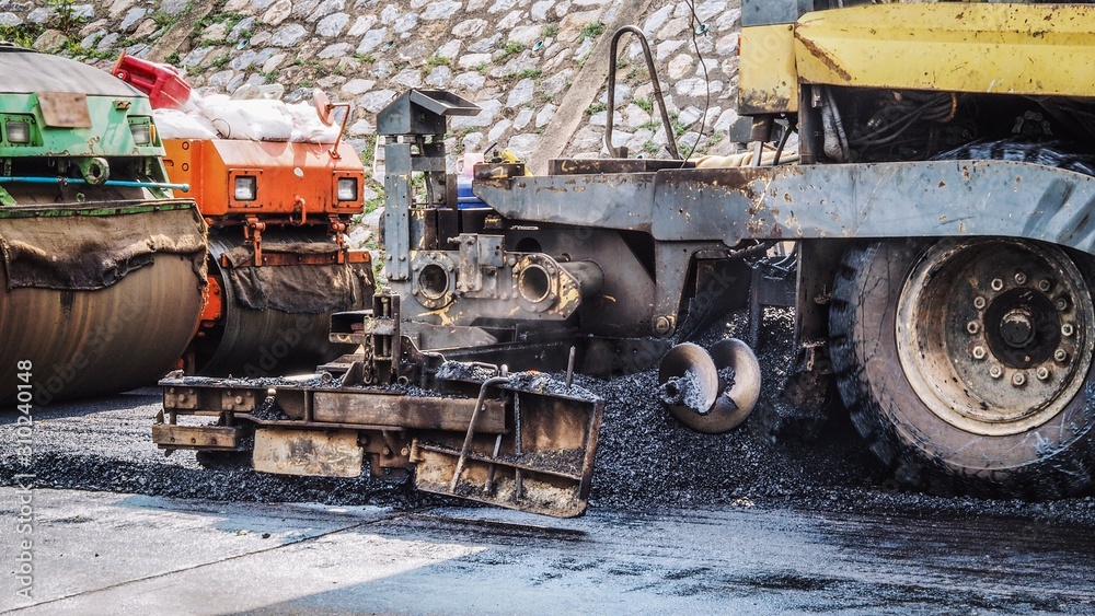 Industrial pavement, road construction works with roller compactor and asphalt finisher machines / vehicles.
