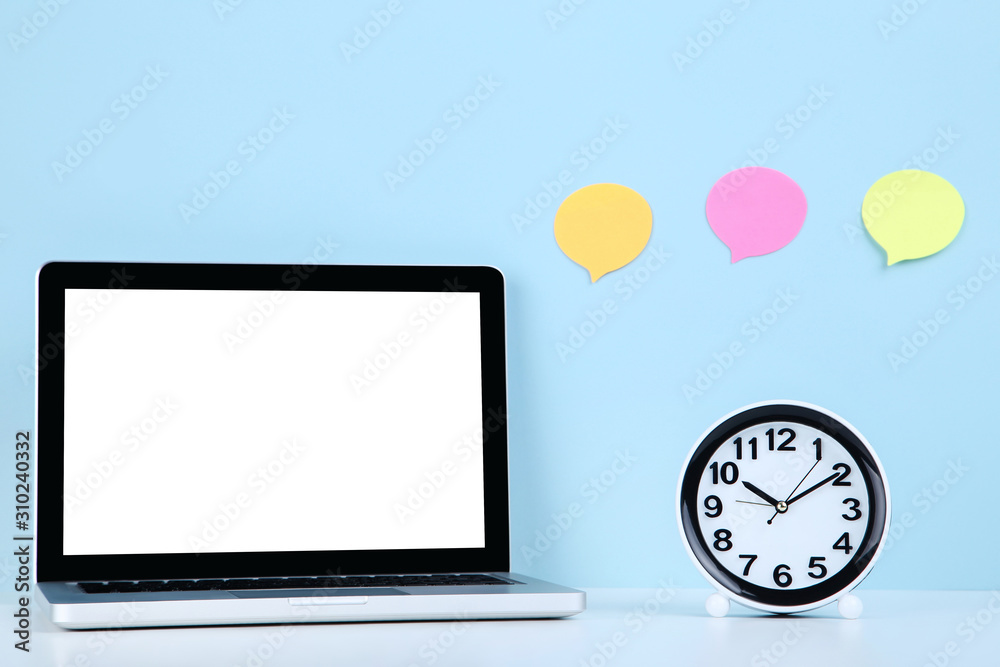 Laptop computer with round clock and blank speech of bubbles on blue background Laptop computer with round clock and blank speech of bubbles on blue background