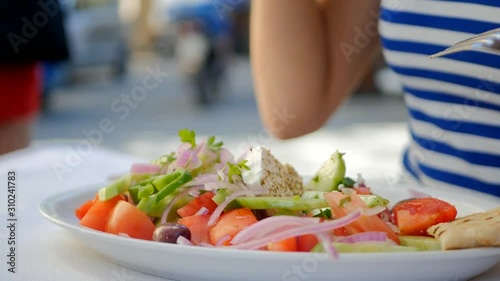 Closeup of woman's hand eating Greece salad and drinking wine photo