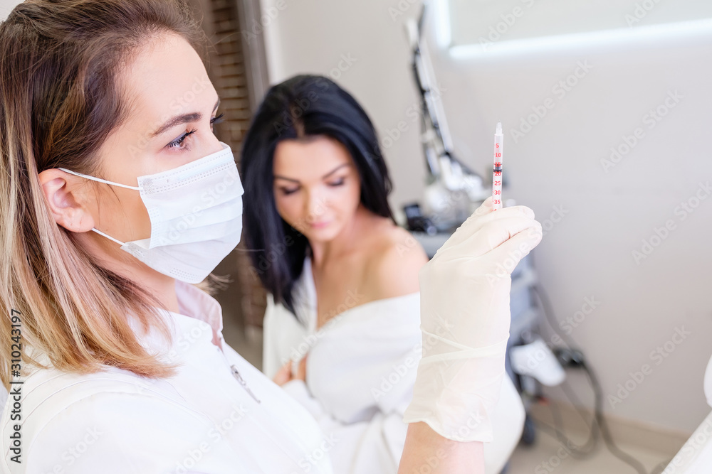 Fototapeta premium An unidentified immunologist picking up a vaccine into a vaccination syringe for a young female client. ?oncept of immunization against diseases and viruses. Medicine concept