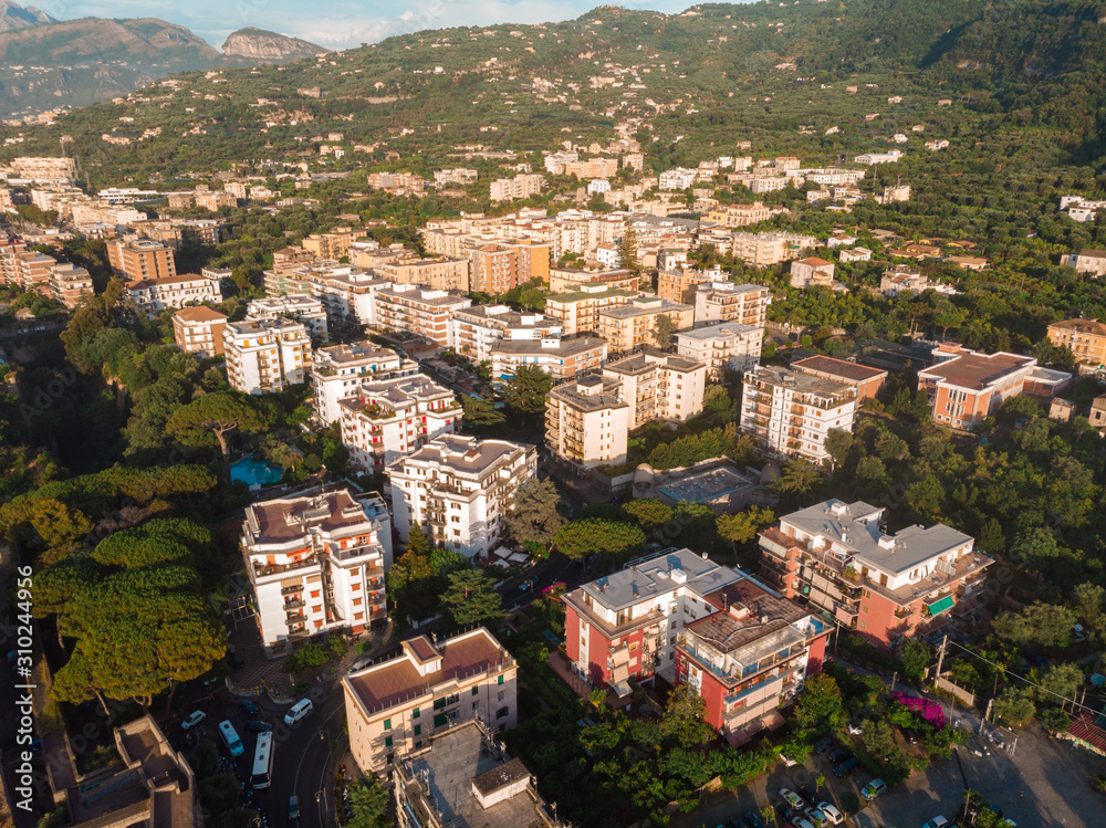 Aerial view on the Sorrento city streets, sunset, houses and Hotels, mountains and buildings in the distance. Travel and vacation concept on Italy. Infrastructure, cars and parking place