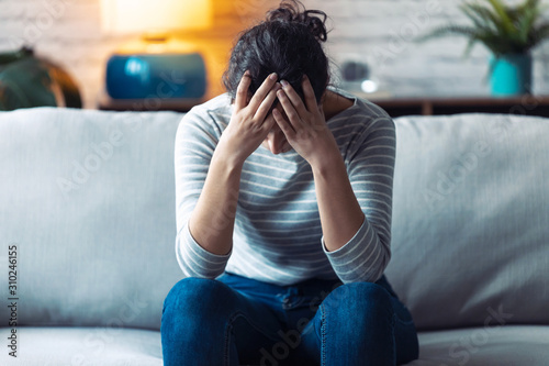 Foto Depressed young woman thinking about her problems while sitting on the sofa at home