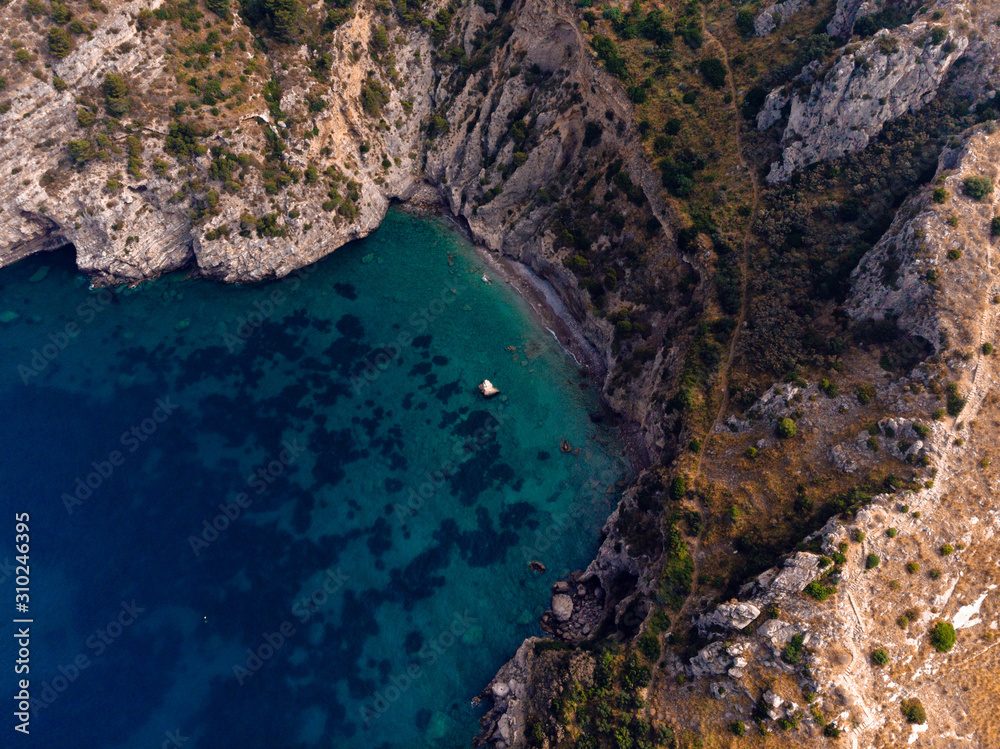 Beautiful top down aerial view of wilderness bay and mountains on sunrise, hiking to a wild beach, tourist destination place for snorkeling and kayaking. Nerano, Massa Lubrense, Ieranto bay, Italy