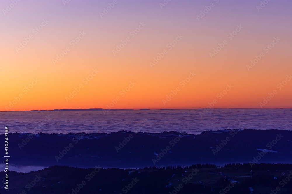 Colorful sky after sunset. Hills sticking out of fog. Baden-Wuerttemberg, Germany