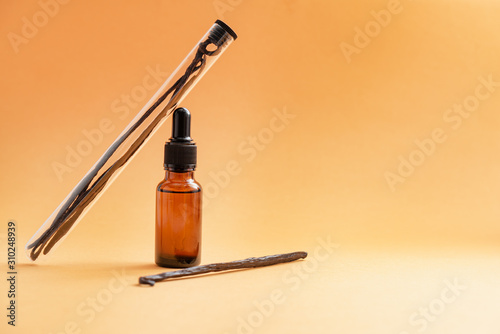 Vanilla in glass tube and cosmetics bottle with oil extract.