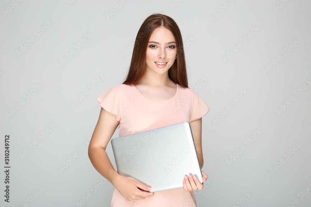 Young woman holding laptop computer on grey background Young woman holding laptop computer on grey background