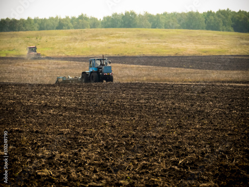 Tractors plow plowland on an autumn clear day