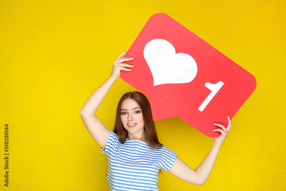 Young woman holding paper card with heart and number one on yellow background