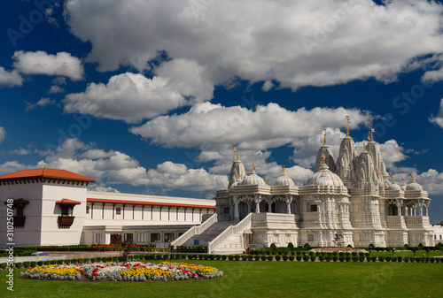 BAPS Shri Swaminarayan Mandir and Haveli Hindu Temple Complex with flower bed on a sunny afternoon photo