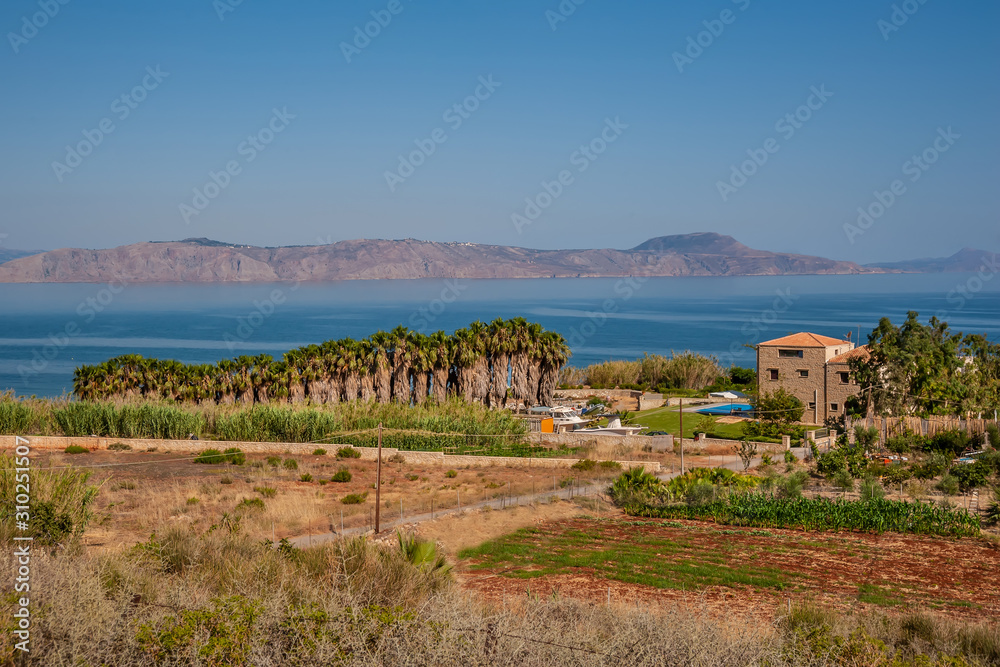 Palm grove and house by the sea on a background of mountains