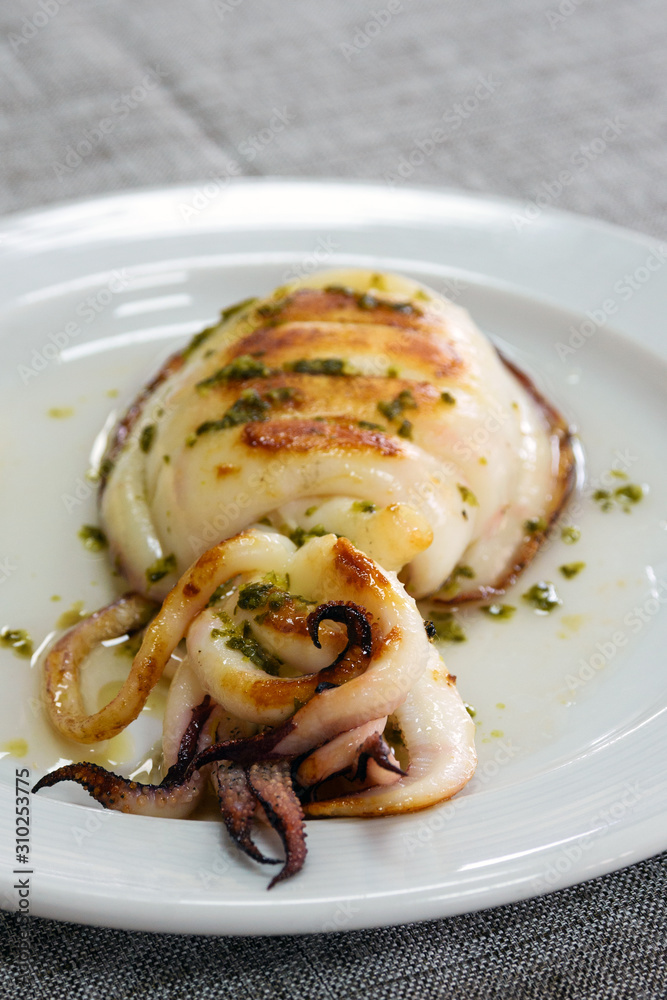 Grilled cuttlefish with sauce on a white plate. Delicious wholesome dinner  at a Spanish fish restaurant. A gastronomic trip to Valencia. Photos |  Adobe Stock