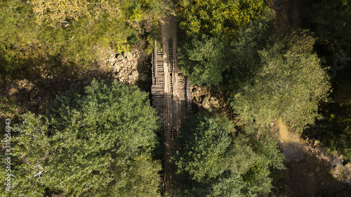 old wooden bridge over a dry riverbed with a rocky bottom in the forest