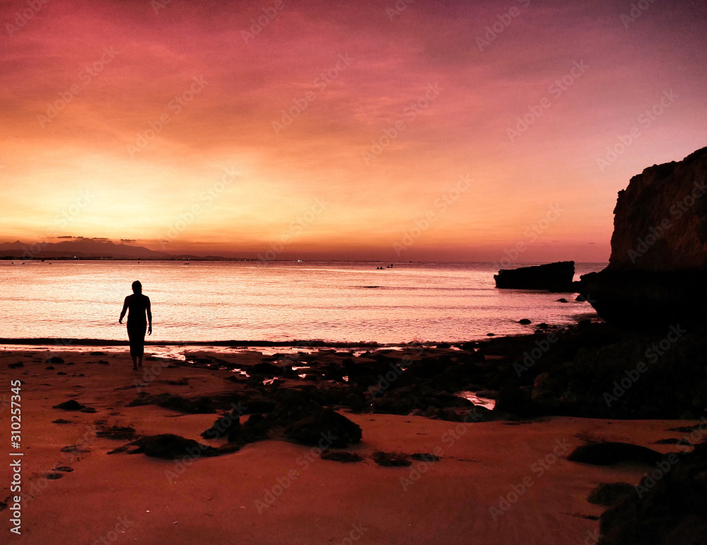 silhouette of man on beach at sunset
