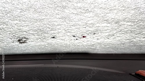 snow melts quickly on the windshield of the car, view from the inside of the car. Time lapse from frozen glass to fully thawed. Heated glass and webasto heats the interior photo