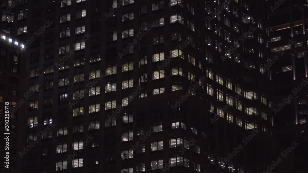 Typical generic night time exterior establishing shot of luxury apartment building facade NX. Lock down shot up at lights in windows