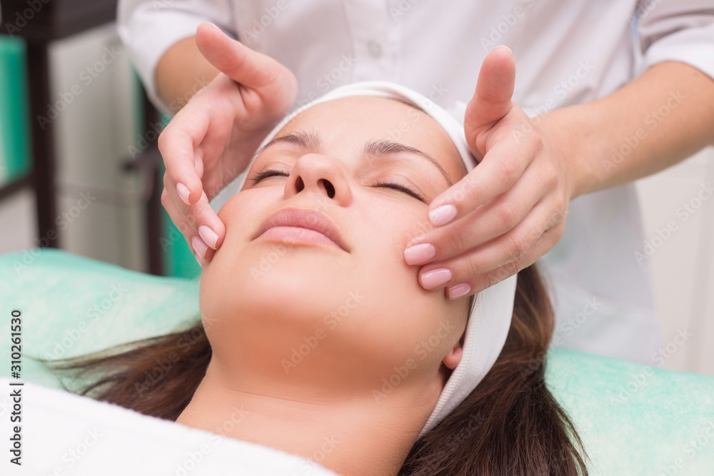 Girl massage therapist does facial massage with a beautiful woman. Hands are closing. Massage room Girl massage therapist does facial massage with a beautiful woman. Hands are closing. Massage room