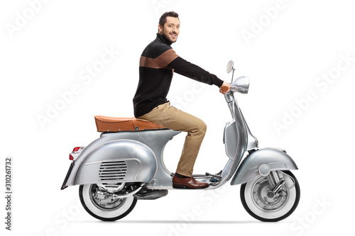 Young elegant man riding a vintage scooter and looking at the camera