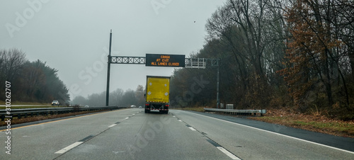 Φωτογραφία Electric warning sign over yellow box truck on highway warning of crash ahead an