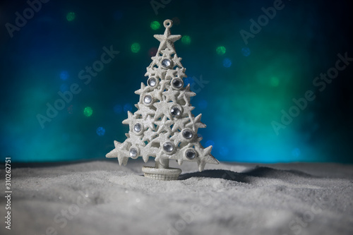 Empty space for your text. Christmas decorations. Fir tree standing on snow with beautiful holiday decorated background and traditional holiday attributes. Selective focus