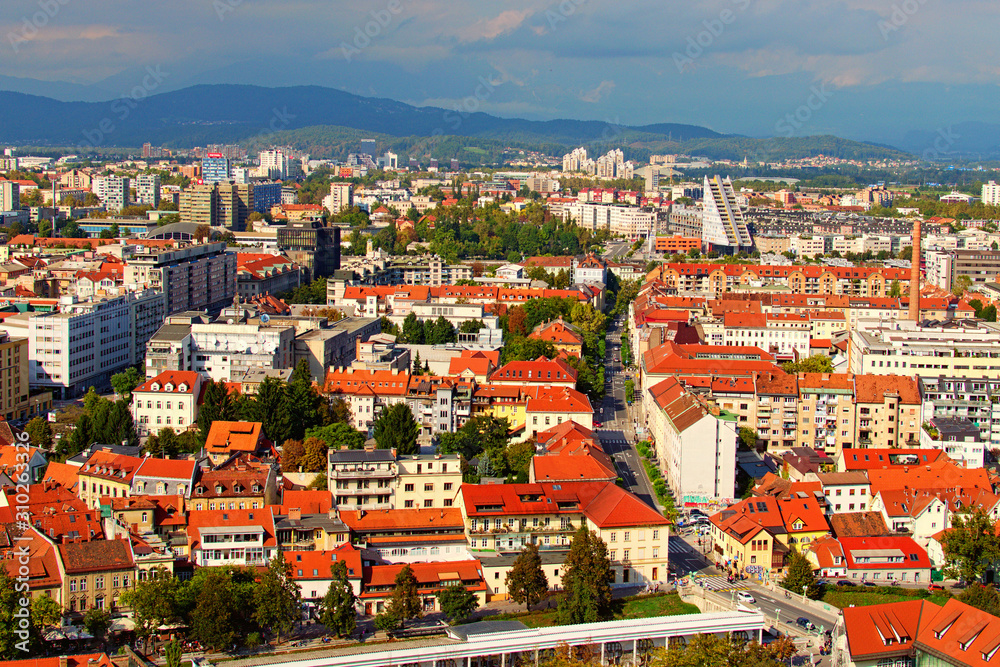 Ljubljana, Slovenia-September 29, 2019:Picturesque aerial view of old part or the city at sunny autumn day. Ancient buildings with red tile roofs, mountain range in the back ground. Vibrant sky