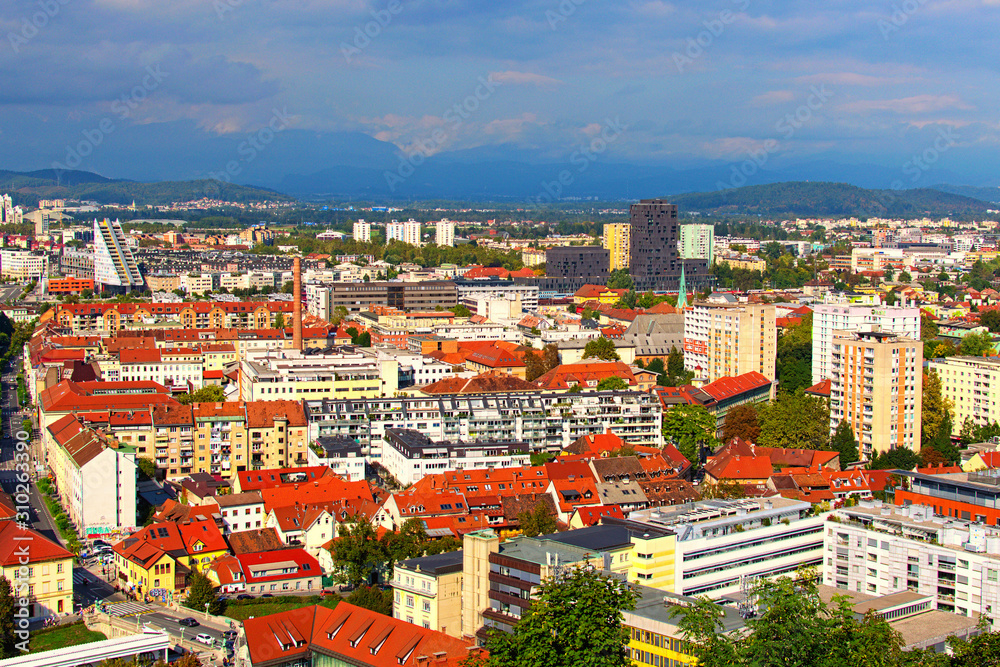 Ljubljana, Slovenia-September 29, 2019: Scenic aerial view of old part or the city at sunny autumn day. Ancient buildings with red tile roofs, mountain range in the back ground. Colorful vibrant sky