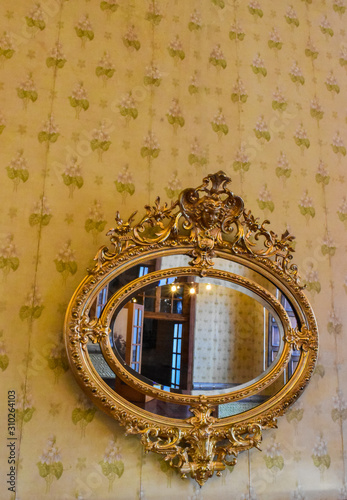Side view of vintage golden mirror hanging decorated wallpaper