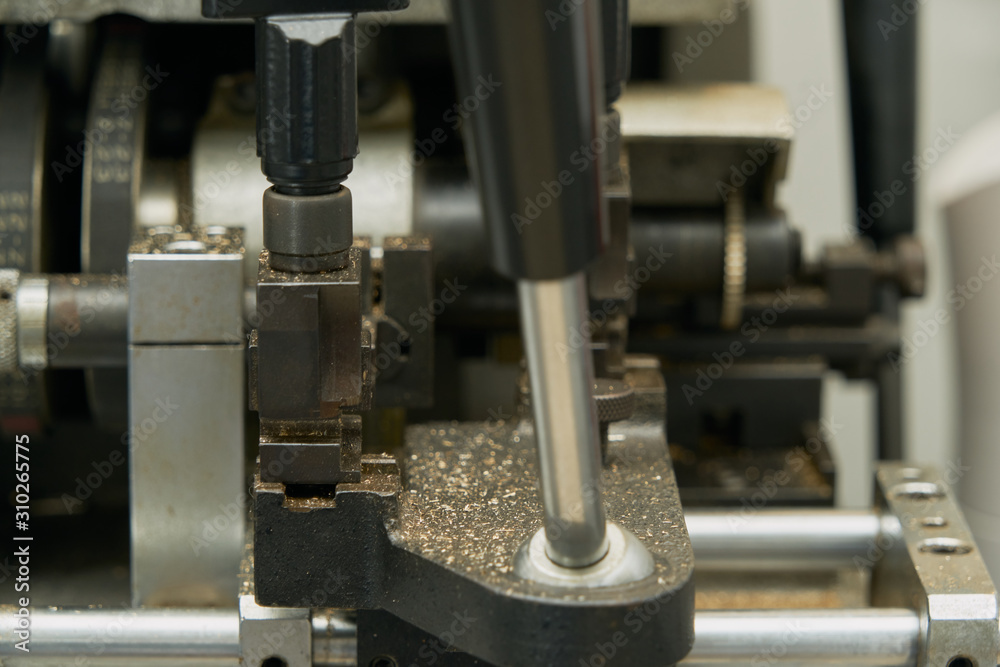 Levers, belts and elements of a key cutting machine. Image of the mechanisms and of the shavings of excess metal. Levers, belts and elements of a key cutting machine. Image of the mechanisms and of the shavings of excess metal.