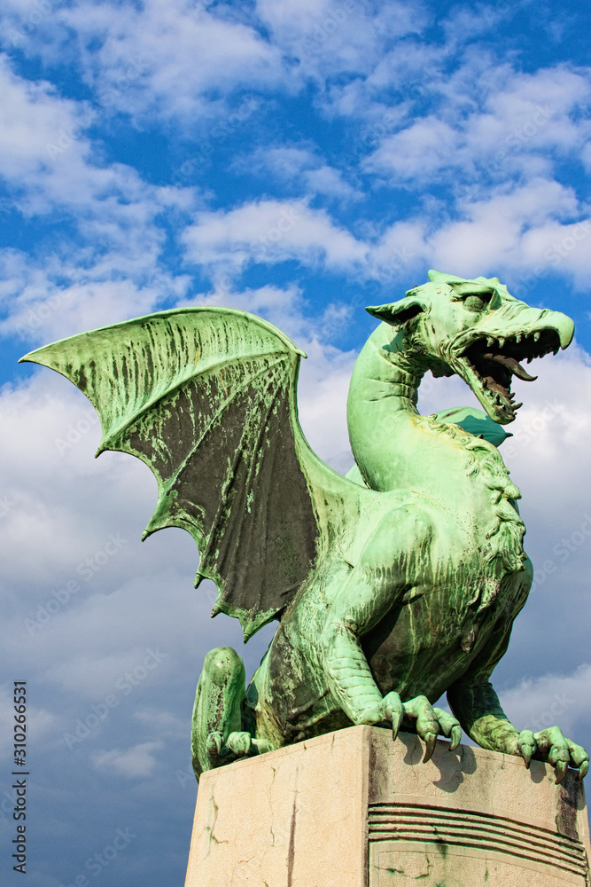Green Dragon is main symbol of Ljubljana. It is one of four statues that adorn the famous Dragon bridge (Zmajski most). Travel and tourism concept. Vibrant sky in the background. Ljubljana, Slovenia
