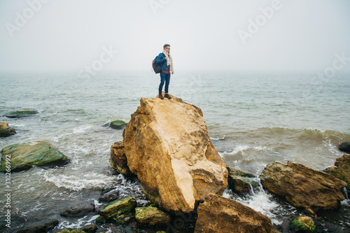 Traveler man stands on a rock on the background a beautiful sea. Place for text or advertising