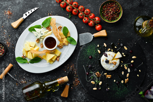 Cheese dishes, cheese slicing on a black stone background. Top view. free space for your text. Rustic style.