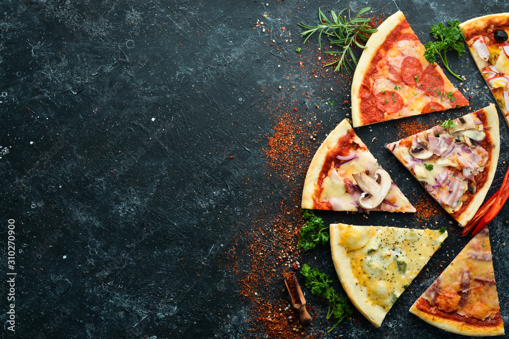 Assortment of pizza sliced on black stone background. Top view. free space for your text. Rustic style.