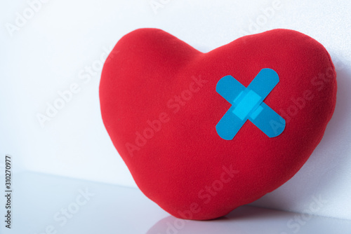 red wound heart with bandage on white background