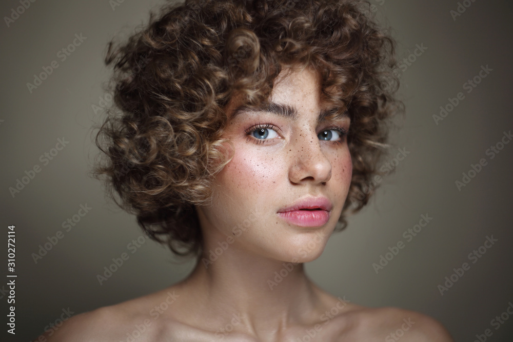 Vintage style portrait of young beautiful freckled girl with curly hair and clean makeup, selective focus