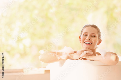Beautiful young woman taking bath at home