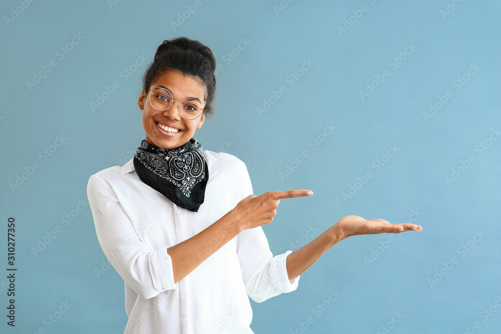 Beautiful African-American woman pointing at something on grey ...