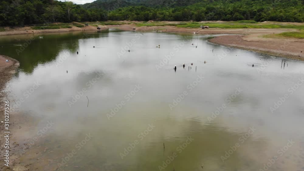 Aerial view of fisherman with a fishing rod on the river bank. Man fisherman catches a fish. Concept of a rural getaway. Fishing in river. Aerial view of fisherman with a fishing rod on the river bank. Man fisherman catches a fish. Concept of a rural getaway. Fishing in river.