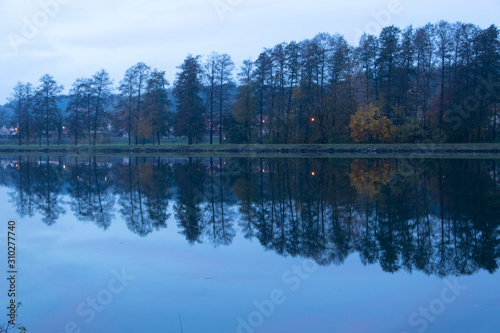 Morgendämmerung am Flussufer des Main bei Elsenfeld. Zu sehen sind wunderschöne Spiegelungen der Bäume und des gegenüberliegenden Ufers. Elsenfeld liegt in Franken, Bayern gegenüber von Obernburg.