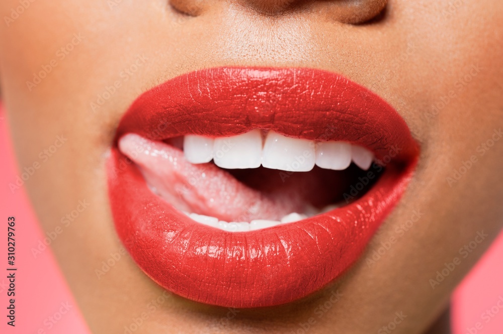 Obraz premium Cropped image of woman licking red lipstick