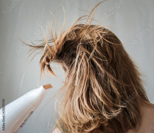 girl drying  her hair by a hair dryer