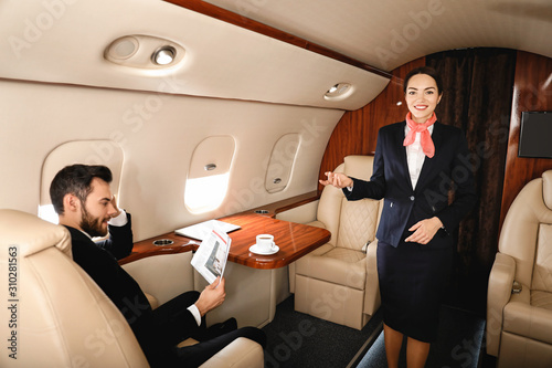 Air hostess and businessman on board the modern private airplane