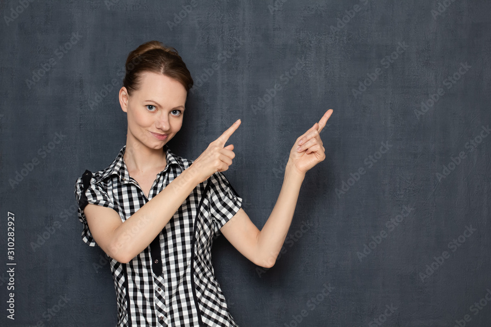 Portrait of happy cute girl pointing with index fingers at copy space