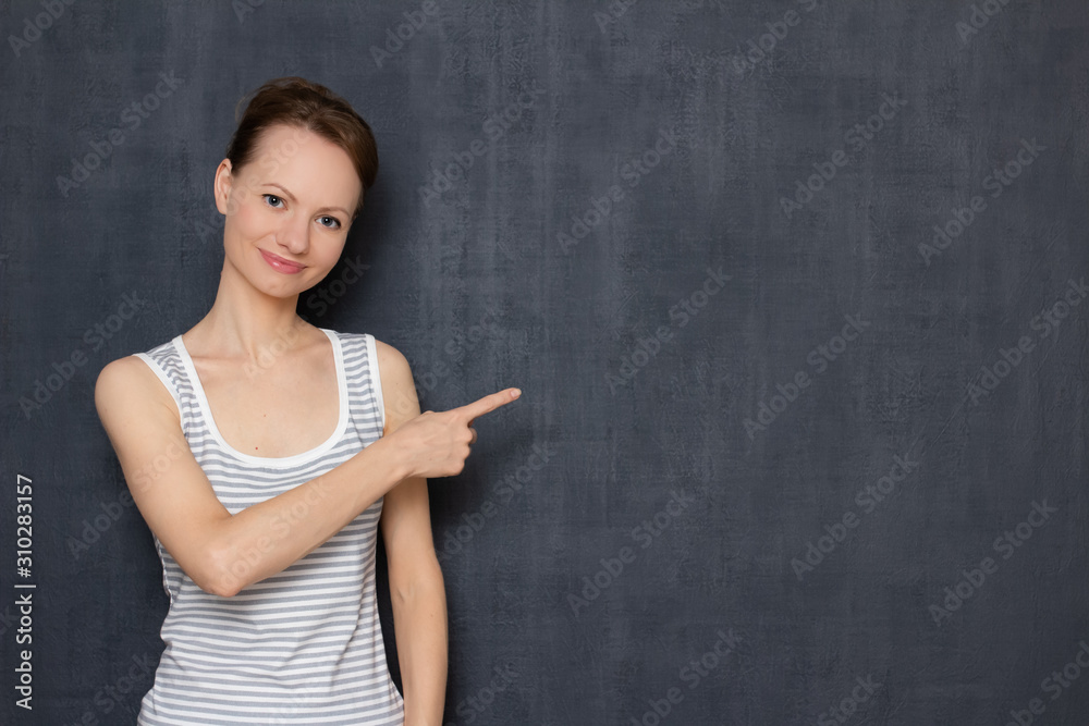 Portrait of happy friendly young woman pointing at copy space on right Portrait of happy friendly young woman pointing at copy space on right
