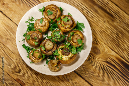 Baked mushrooms in plate on wooden table. Top view