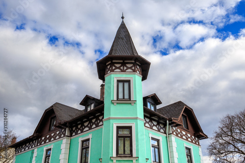 Historical traditional colorful corner house in Starnberg, Bavaria, Germany - part of the facade. Stormy rain clouds and a V-shaped patch of blue sky.