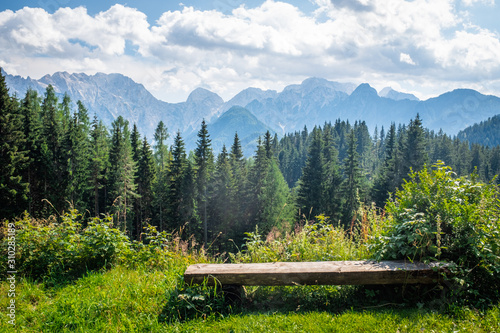 Wooden bench in front of Kamnik–Savinja Alps in Slovenia photo